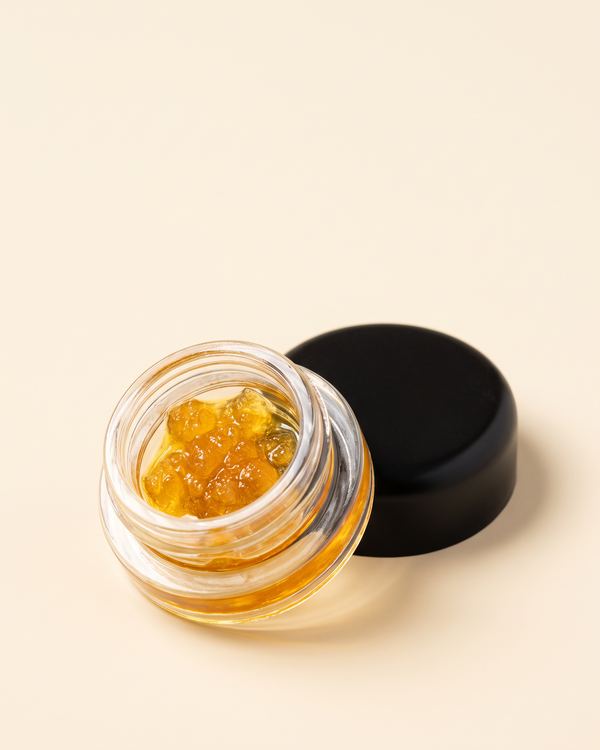 A small glass jar of concentrate with its lid beside it